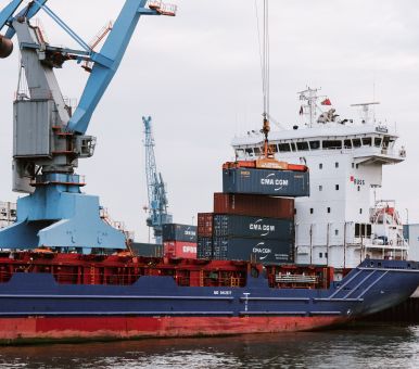 Cargo ship being loaded with shipping containers by a crane at a port