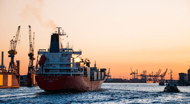 Cargo ship at sunset with cranes in the background - Air and sea Freight Singapore
